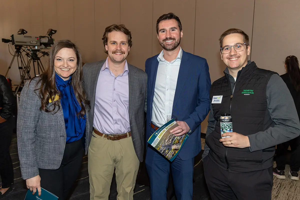 A group of guests stand together posing at the social at the annual meeting.