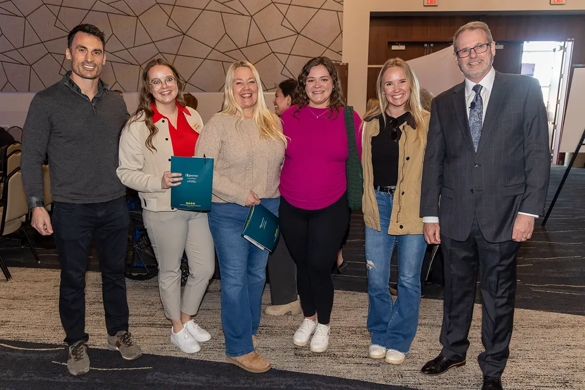 A group of guests stand together posing at the social at the annual meeting.