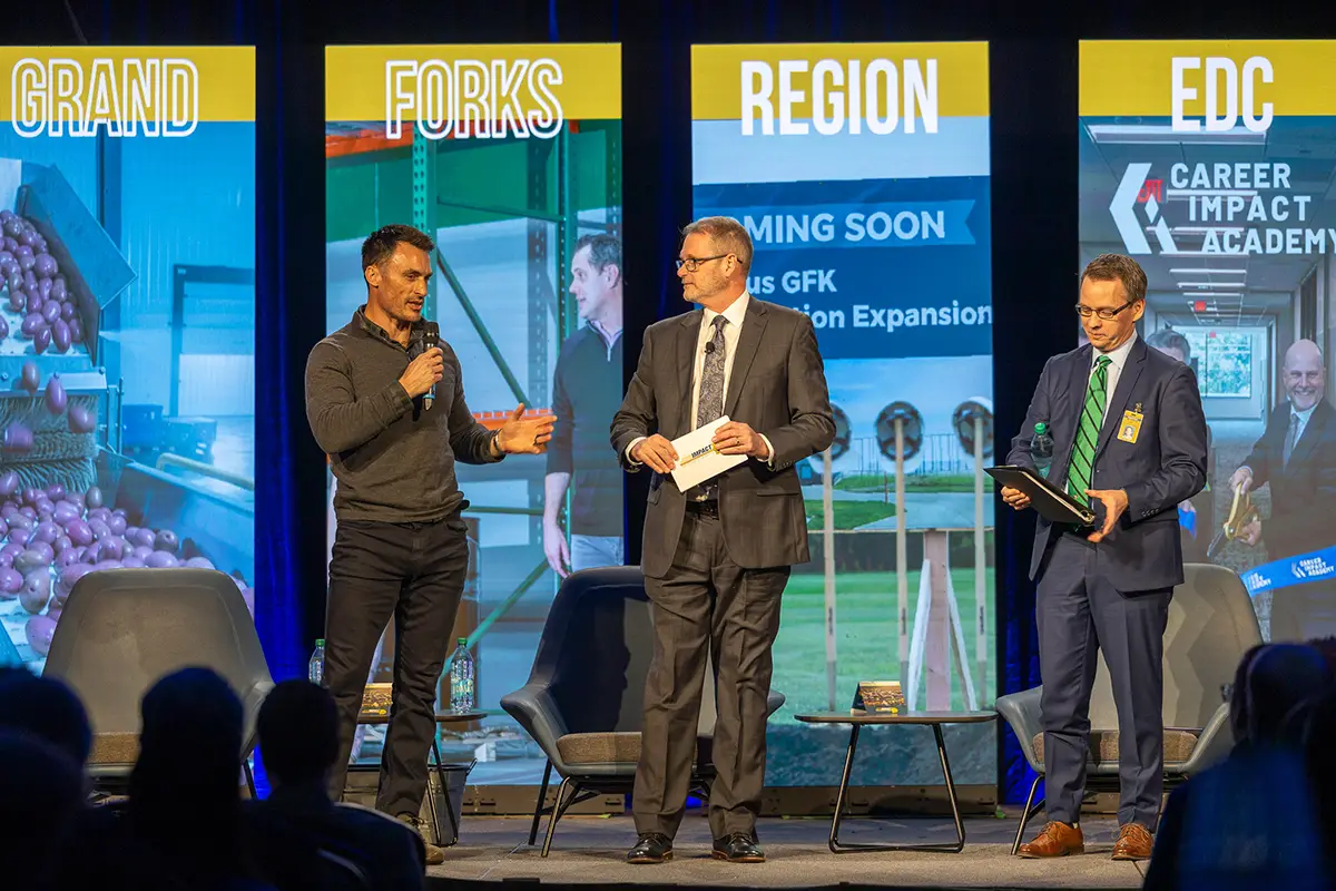 City of Grand Forks Mayor Brandon Bochenski stands on stage delivering remarks next to edc president & Ceo keith lund at the 2026 annual meeting.